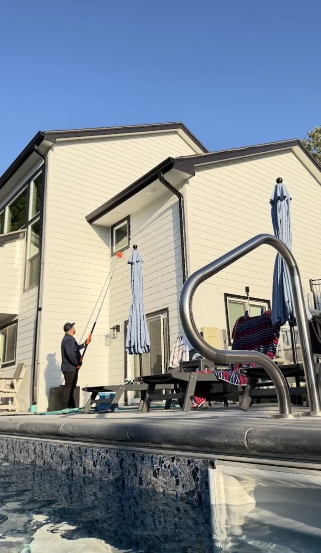 Mission Pest Control technician removing webs and pest harborages around a residential window
